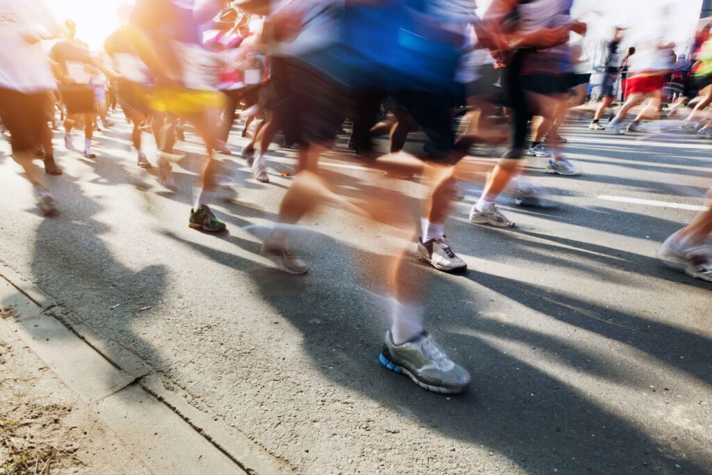 Marathon runners in motion. Running in the city, sun shining.